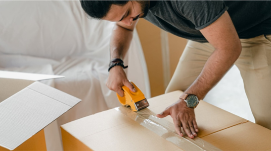 Man taping up a cardboard box with gaffa tape